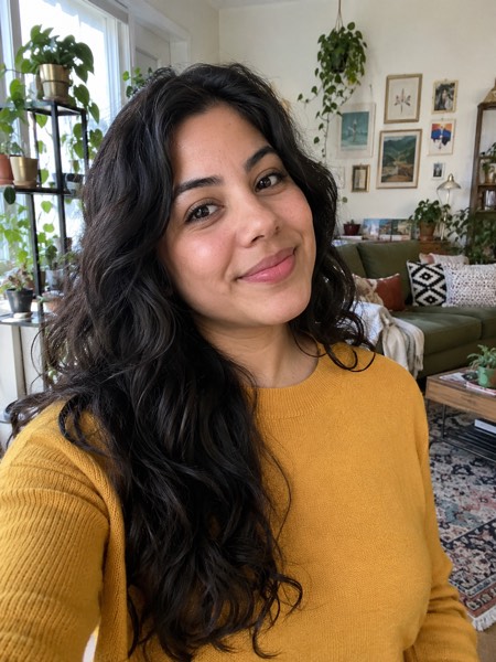 Example phone selfie of a woman in a mustard sweater in a busy living room
